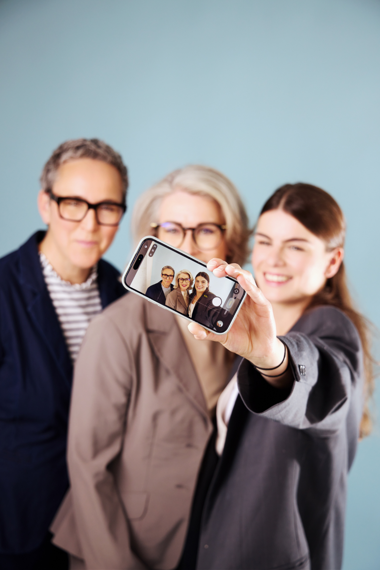 Die drei CoCreAGE-Beraterinnen zeigen gemeinsam ein Smartphone in die Kamera.